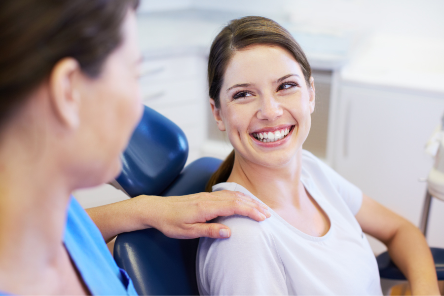 Brunette woman in a dental chair smiles because she is relaxed at the dentist